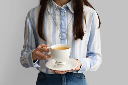 Woman drinking tasty coffee on gray background, closeupの写真素材