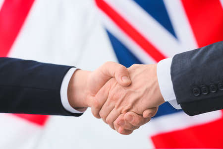 Business people handshaking against the flags of Great Britain and Englandの写真素材