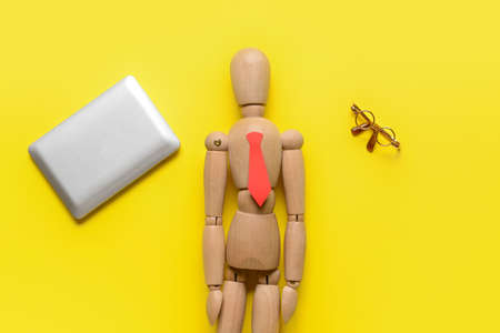 Mannequin with tiny laptop and eyeglasses on color backgroundの写真素材