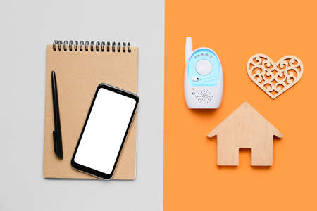 Mobile phone with office supplies, baby monitor, figure of house and heart on color background. concept of balanceの写真素材