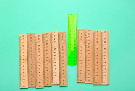 Green ruler among wooden ones on color background. Concept of uniquenessの写真素材