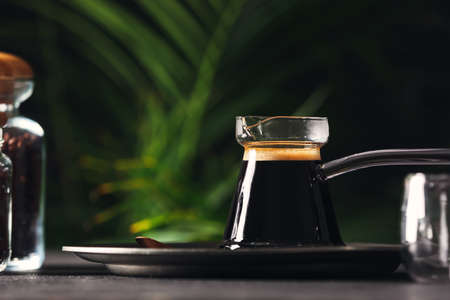 Cezve with hot turkish coffee on table