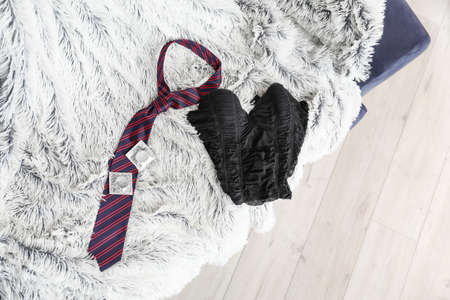 Male necktie and female lingerie with condoms on bed after romantic date