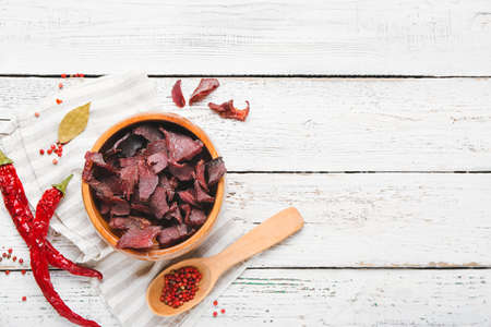 Bowl with spicy beef jerky on white wooden backgroundの写真素材