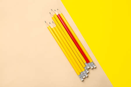 Red pencil among yellow ones on color background. Concept of uniquenessの写真素材