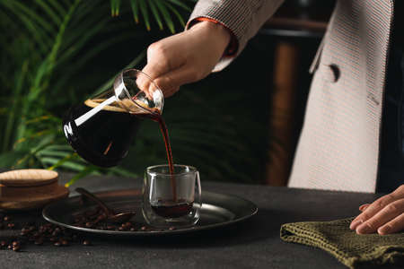 Woman pouring delicious turkish coffee in glass cup at tableの写真素材