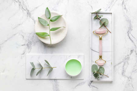 Face massage roller with cosmetic cream on white backgroundの写真素材