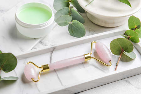 Face massage roller with cosmetic cream on white backgroundの写真素材