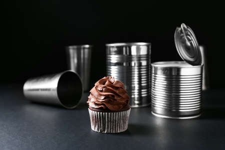 Tasty chocolate cupcake with tin cans on dark backgroundの写真素材