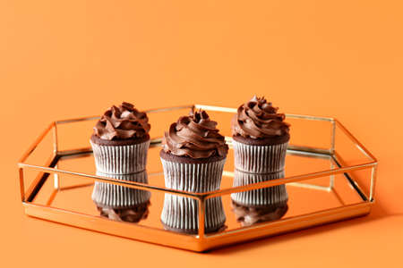 Tray with tasty chocolate cupcakes on color backgroundの写真素材
