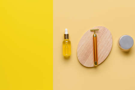 face massage roller with cosmetic products on color backgroundの写真素材