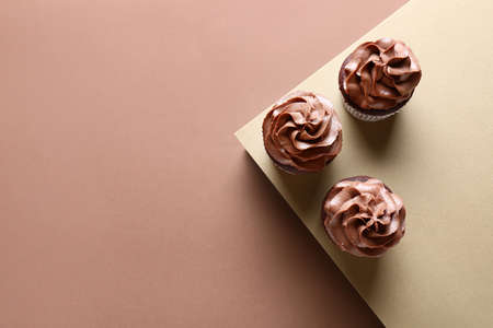 Tasty chocolate cupcakes on brown background