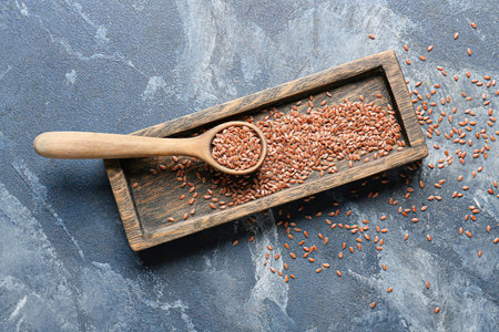 Tray and spoon with flax seeds on color backgroundの写真素材