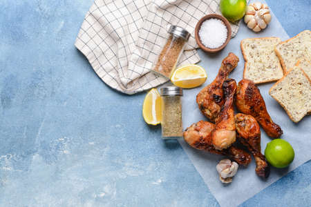 Tasty cooked chicken drumsticks with bread and spices on color backgroundの写真素材