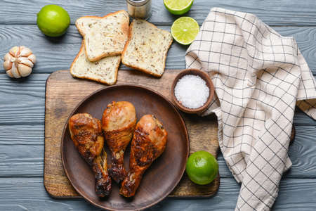Plate with tasty cooked chicken drumsticks and bread on tableの写真素材
