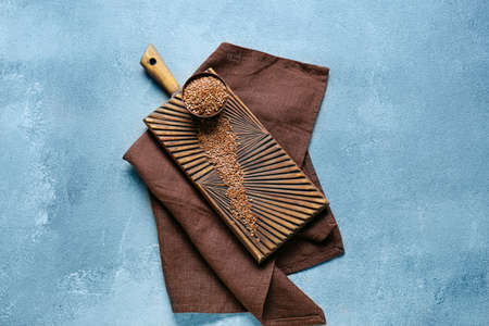 Bowl and board with raw flax seeds on color background