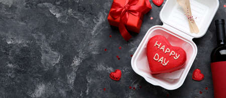 Tasty bento cake and gift for Valentine's Day with bottle of wine on dark background with space for textの写真素材