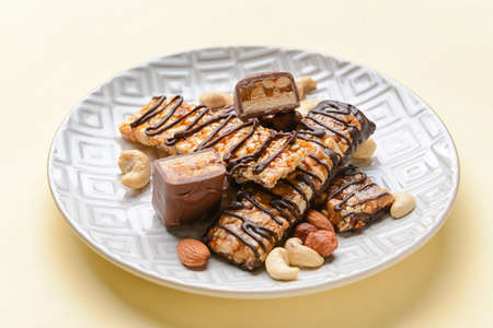 Plate with tasty chocolate nut bars on light background