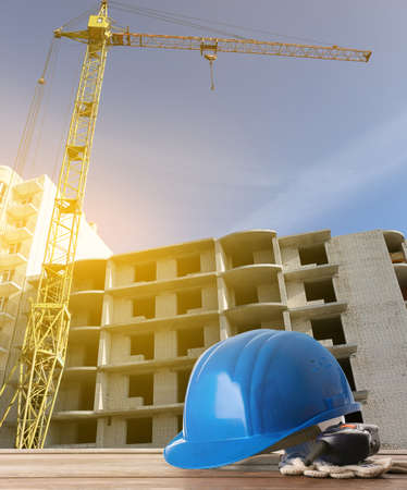 Safety hardhat with gloves and radio transmitter on wooden table at construction site