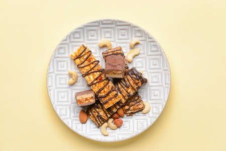 Plate with tasty chocolate nut bars on light backgroundの写真素材