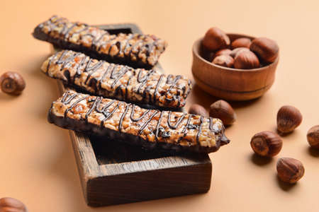 Board with tasty chocolate nut bars on color background