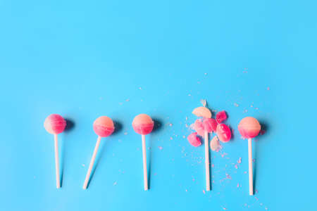 Broken lollipop among whole ones on color background. concept of uniquenessの写真素材