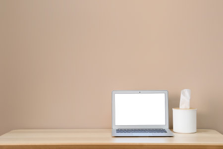 Modern workplace with laptop and tissue box near color wallの写真素材