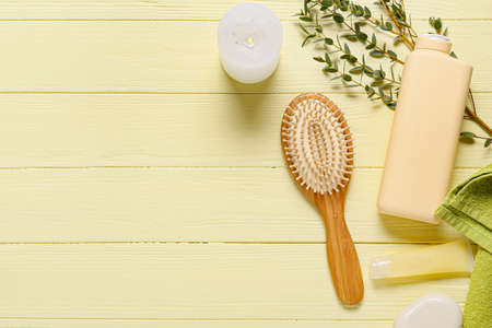 Composition with hair brush, burning candle and bath supplies on color wooden backgroundの写真素材