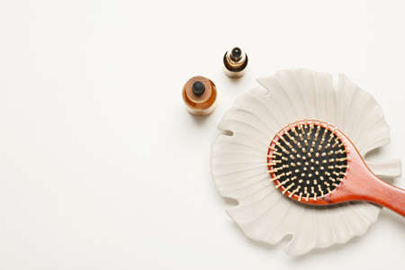 Plate with hair brush and bottles of cosmetic products on white backgroundの写真素材