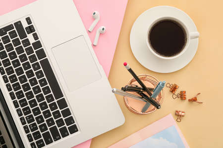 Modern devices with stationery and cup of coffee on color backgroundの写真素材