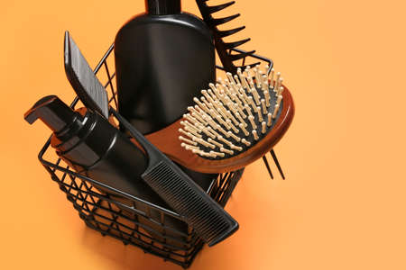 Basket with hair brush, combs and cosmetics on color backgroundの写真素材
