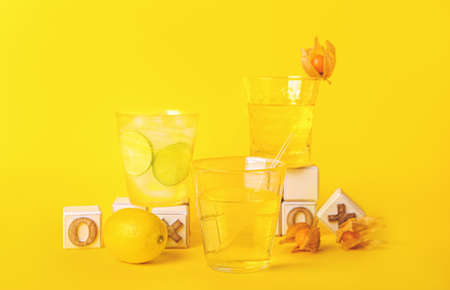 Glasses of fresh cocktails with physalis and citrus fruits on color backgroundの写真素材