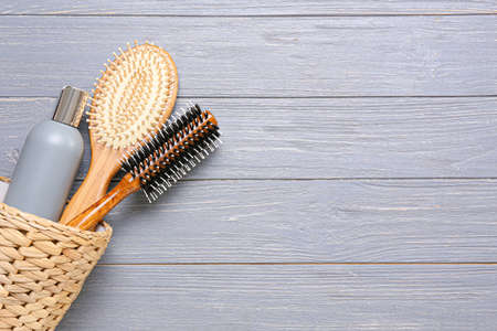 Basket with hair brushes and bottle of cosmetic product on wooden backgroundの写真素材