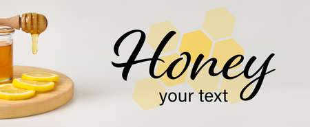 Glass jar of sweet honey with dipper and lemon slices on light background with space for textの写真素材
