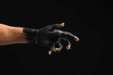 Male hand covered with black and golden paint on dark backgroundの写真素材