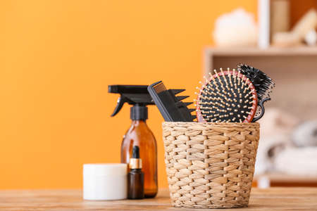 Basket with hairdresser's tools and cosmetics on table in roomの写真素材