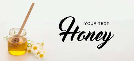 Jar of sweet honey and chamomile flowers on light background with space for textの写真素材