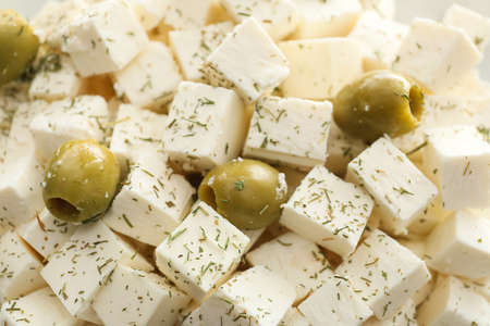 Delicious pieces of feta cheese with olives as backgroundの写真素材