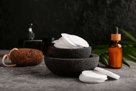Bowl with cotton pads and bottle of cosmetic product on grunge table, closeupの写真素材