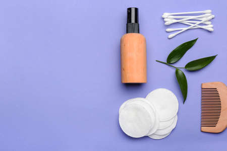 Cotton pads, swabs, comb and bottle of cosmetic product on color backgroundの写真素材