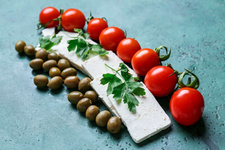 Tasty feta cheese, tomatoes and olives on color background