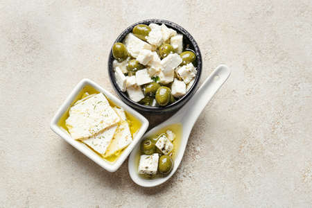 Bowls and spoon with tasty feta cheese, oil and olives on light backgroundの写真素材