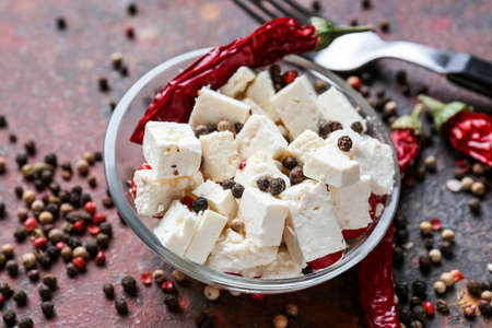 Bowl with tasty feta cheese and chili pepper on grunge backgroundの写真素材