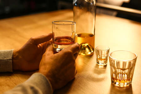 Senior man with glass of drink late in the evening at home, closeupの写真素材