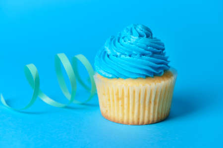 Tasty Birthday cupcake and ribbon on color background, closeupの写真素材