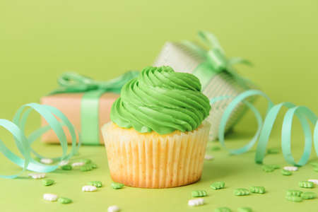 Tasty Birthday cupcake with gifts and ribbons on color background, closeupの写真素材