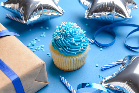 Tasty Birthday cupcake, balloons, gift and candles on color background, closeupの写真素材