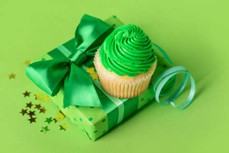 Tasty Birthday cupcake with gift and ribbon on color backgroundの写真素材