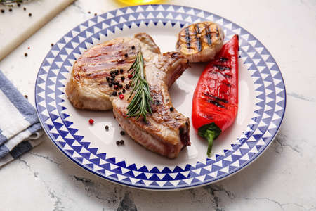 Plate with tasty steak and spices on light background