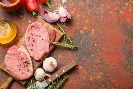 Board with fresh raw meat and spices on grunge backgroundの写真素材